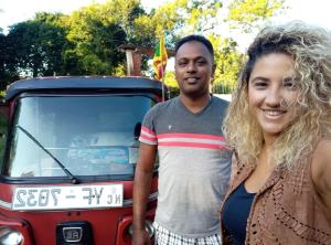 a man and a woman standing next to a red car at Habarana Dulwan Guest House in Habarana