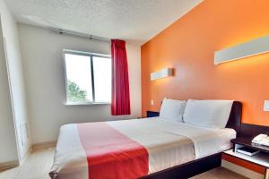 a bedroom with a bed with an orange wall at Motel 6-Lewisville, TX - Dallas in Lewisville