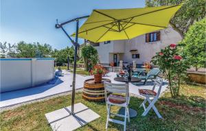 żółty parasol na dziedzińcu ze stołem i krzesłami w obiekcie Apartment Glavani Iv w mieście Barban