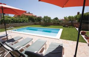 basen z krzesłami i parasolem w obiekcie Stunning Home In Medulin With 4 Bedrooms, Wifi And Outdoor Swimming Pool w Medulinie