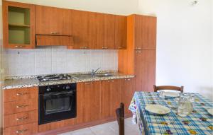 uma cozinha com armários de madeira e uma mesa com um lavatório em Lovely Home In Zambrone With Kitchen em Zaccanopoli