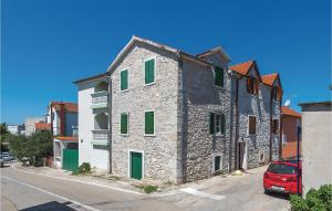 an old stone building with green shutters on a street at Amazing Home In Vodice With Kitchen in Vodice