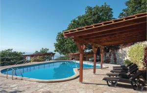 a swimming pool with a wooden pergola and chairs at Stunning Home In Podstrana With 7 Bedrooms, Jacuzzi And Outdoor Swimming Pool in Podstrana