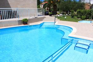 a large swimming pool with blue water in a yard at Apartments Grand Pinea in Čilipi