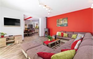 a living room with a couch and a red wall at 4 Bedroom Beautiful Home In Kunj in Kunj