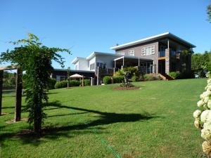 ein großes Haus mit Rasen davor in der Unterkunft The Orchard in Whakamarama