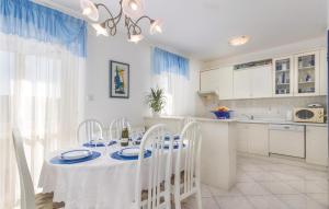 une cuisine avec une table et des chaises et une cuisine avec des placards blancs dans l'établissement Cozy Apartment In Rabac With Wifi, à Rabac