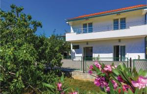 une maison blanche avec une clôture et des fleurs roses dans l'établissement Beautiful Home In Poljica With Kitchen, à Poljica