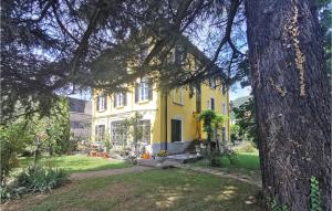 Una casa amarilla con un árbol delante. en Cozy Apartment In Nembro With House A Mountain View en Nembro
