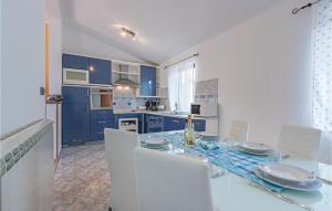 a kitchen with blue cabinets and a table with white chairs at Gorgeous Home In Vodnjan With Kitchen in Vodnjan