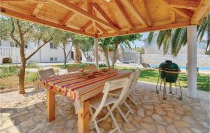 un tavolo e sedie in legno sotto un padiglione con griglia di Amazing Home In Zdrelac With Wifi a Ždrelac