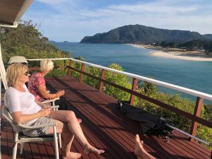two women sitting on a balcony looking at the ocean at Tairua Treasure on Mount Paku in Tairua
