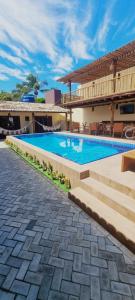 a swimming pool with stairs next to a house at Pousada Lua Nova Pipa Chales com Hidromassagem e Jacuzzi in Pipa