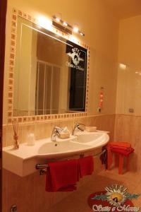 a bathroom with a sink and a mirror and red towels at Hotel Sette E Mezzo in Castelluccio Superiore