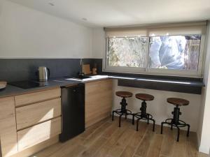 a kitchen with three bar stools and a window at La Hotte des écureuils in Château-Thierry