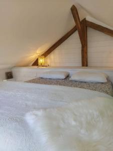 een groot wit bed met 2 kussens in een kamer bij La Hotte des écureuils in Château-Thierry