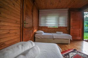 two beds in a room with wooden walls and a window at şeker bungalov in Cıralı