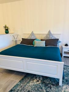 a large white bed with blue sheets and pillows at Ferienwohnung Emma an der Romantischen Straße in Weikersheim