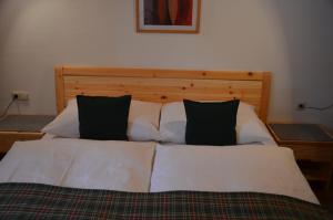 uma cama com lençóis brancos e almofadas pretas em Landhaus St. Georg em Sankt Martin am Tennengebirge