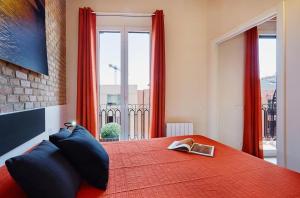 1 dormitorio con 1 cama con manta roja y ventana en Lovely & bright Bogatell beach apartment, en Barcelona