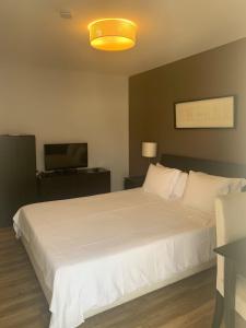 1 dormitorio con 1 cama blanca y TV en Casas de Luanda GH-Miramar en Luanda