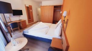 ラインスヴァイラーにあるHotel Rebmannのベッドとデスクが備わる小さなホテルルームです。
