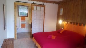a bedroom with a red bed and a window at Paysannerie des Versanes - Chambre et gîte à la ferme in Tour-de-Faure