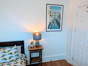 a bedroom with a bed and a table with a lamp at TopHome Stoke Newington in London