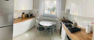 a kitchen with white cabinets and a table and a stove at Apartament Milena in Kudowa-Zdrój