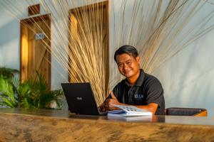 un hombre sentado en una mesa con un portátil en You&Me Resort en Koh Rong Island