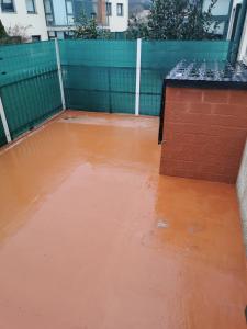 eine leere Terrasse mit einer Ziegelmauer und einem orangefarbenen Boden in der Unterkunft Apartamento vacacional en Brión, 15280 Río pego in Brion