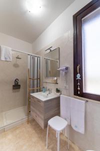 bagno con lavandino, specchio e sedia di Rif Holiday Home Stagnone Marsala a Birgi Vecchi