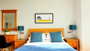 een slaapkamer met een bed met blauwe kussens en een spiegel bij A Room With A View in Brighton & Hove