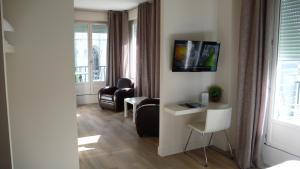 a living room with chairs and a tv on a wall at Hotel cardinal in Rouen