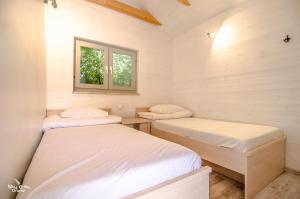 Duas camas num pequeno quarto com uma janela em szumidomek em Mielno