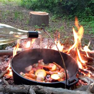 una persona cocinando comida en una sartén sobre un fuego en Glamping v Sadu en Sadská