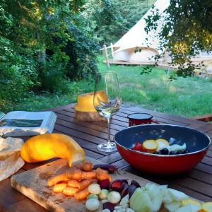 una mesa con un tazón de verduras y una copa de vino en Glamping v Sadu en Sadská