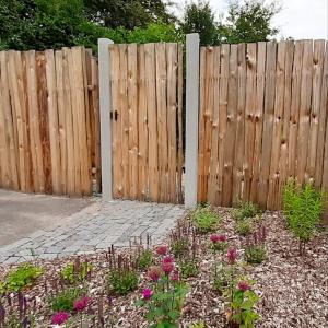 una valla de madera frente a un jardín con flores en Glamping v Sadu en Sadská