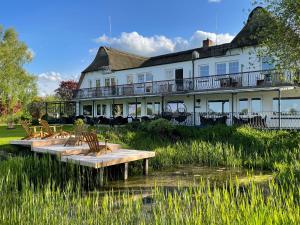 un grand bâtiment blanc avec des bancs devant lui dans l'établissement Hof Norderlück - Das Ostseehotel unter Reet, à Steinberg