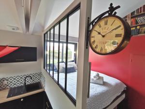 Haute-Goulaine的住宿－Maisonnette avec terrasse et parking，卧室旁边的墙上有大钟
