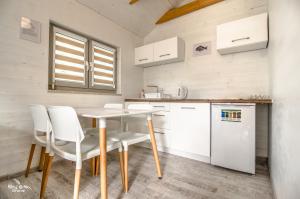 kuchnia z białymi szafkami oraz stołem i krzesłami w obiekcie szumidomek w mieście Mielno