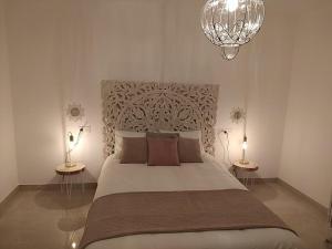 1 dormitorio con 1 cama grande con 2 mesas y lámpara de araña en APARTAMENTO ROMAR CHIC, en Albolote