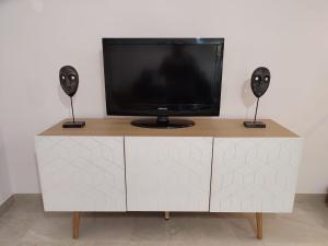 a tv sitting on top of a white cabinet with two speakers at APARTAMENTO ROMAR CHIC in Albolote