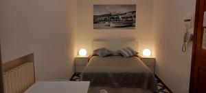 a small bedroom with a bed and two lights on the wall at Residence Villa Chiara in Loano