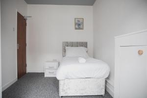 a white bedroom with a bed and a night stand at Leicester House in Leicester
