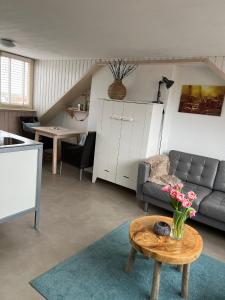 a living room with a couch and a table with flowers on it at Appartement Zuid 5 in Zandvoort