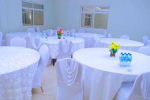 a room filled with white tables and chairs with flowers at Elanacha Hotel in Arusha