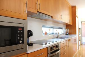 a kitchen with wooden cabinets and a microwave at Villa Martins in Lagoaça
