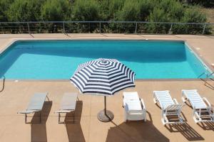 an umbrella and chairs next to a swimming pool at Villa Martins in Lagoaça