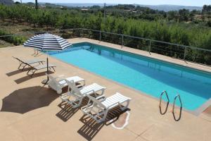 a swimming pool with two chairs and an umbrella at Villa Martins in Lagoaça